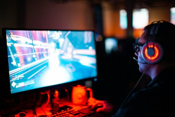 Spieler am Monitor beim Gaming – Beispielhafte Szene für Input Lag Gamer am PC mit Headset, der ein Spiel mit möglichem Input Lag erlebt