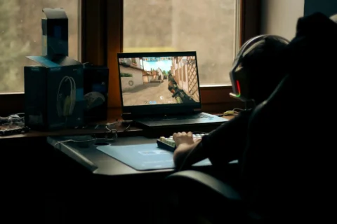 Gamer spielt Shooter am PC, Bilddarstellung auf dem Monitor wirkt unsauber und nicht synchron